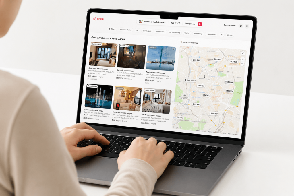 A guest sitting at a desk looking at a listing on the Airbnb website using a laptop.